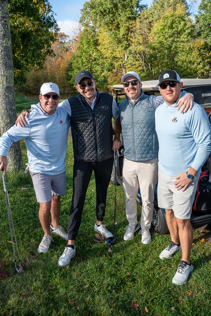 Four golfers posing on the course at the Live Like Brent Classic.